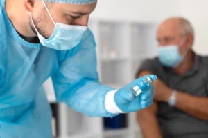 Profissional de saúde preparando vacina contra a gripe para homem sénior — prevenção essencial da gripe depois dos 50 anos.